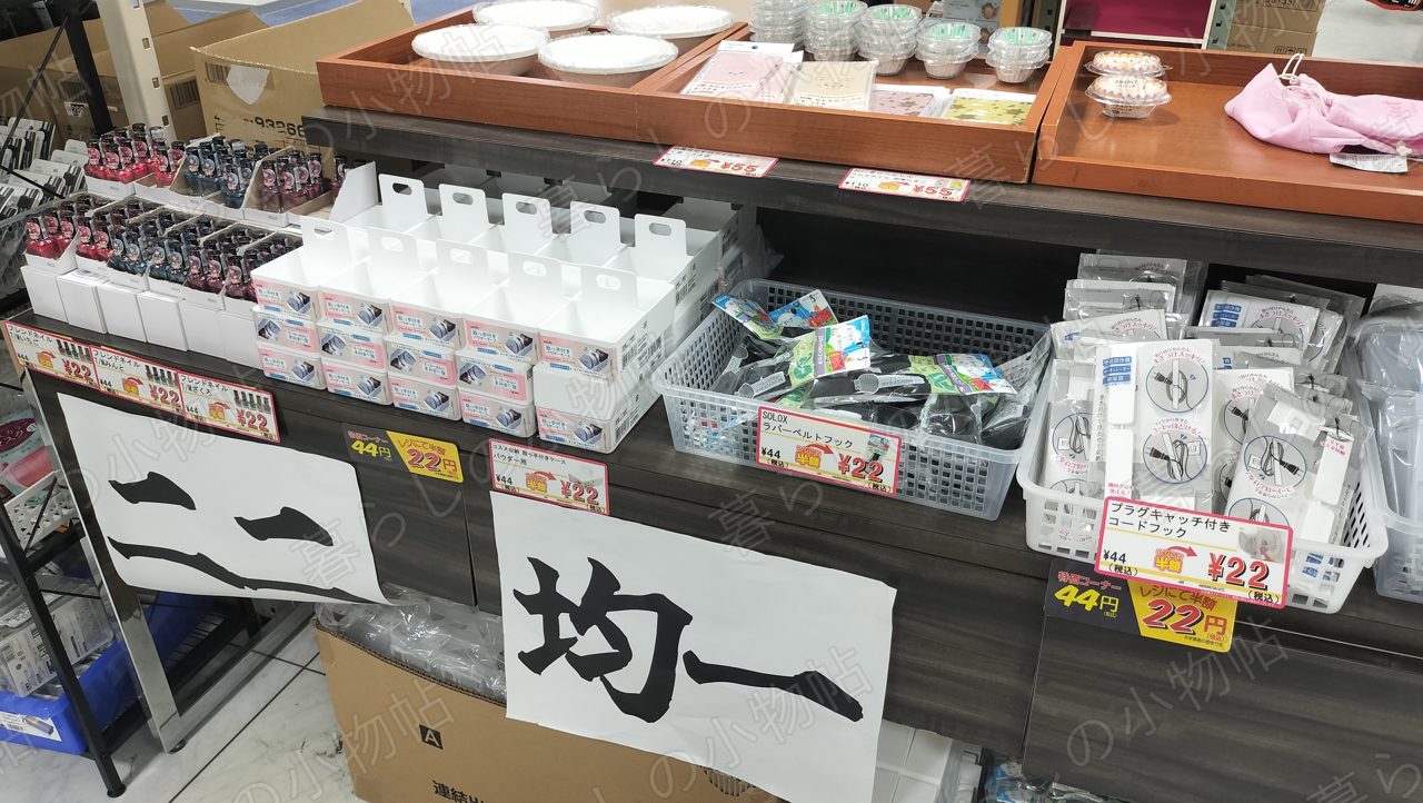222の「二二均一」コーナー。44円が半額の22円になった小物が箱に並ぶ様子を撮影