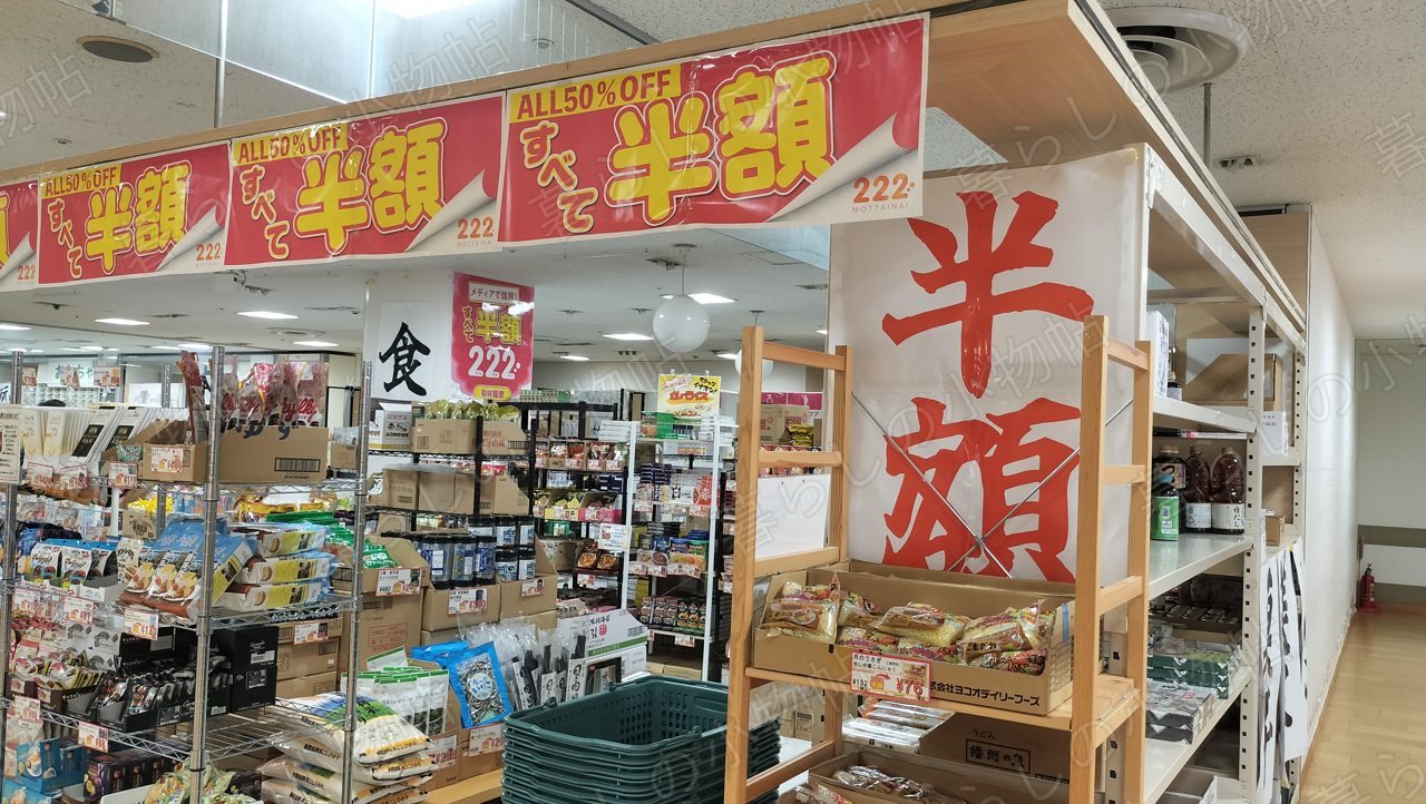 「ALL 50% OFF すべて半額」の横断幕が下がる222の食品コーナー入口を撮影