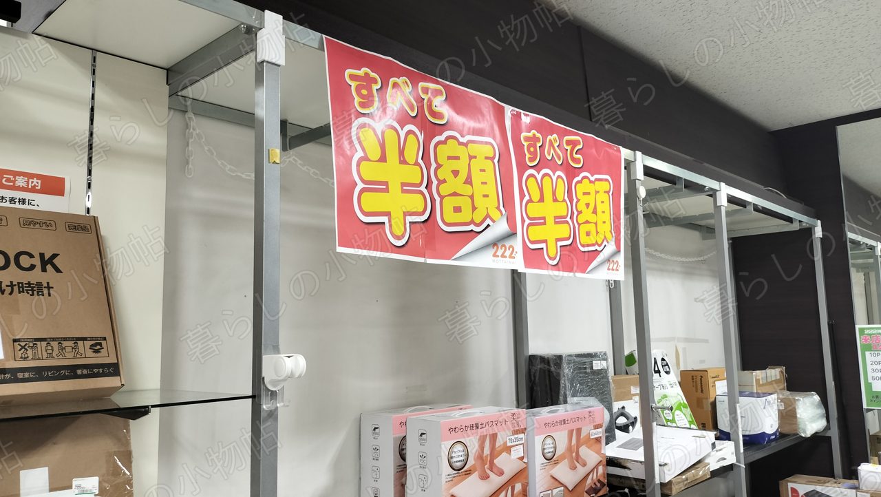 222の売り場に下がる「すべて半額」の赤いPOPと商品棚を撮影