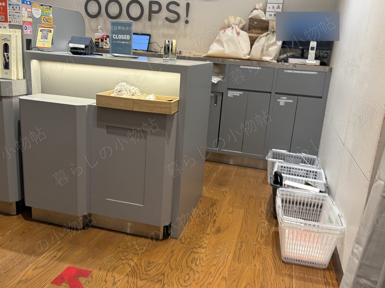 3COINSのレジまわり。壁の「OOOPS!」ロゴと積まれた買い物かごを撮影