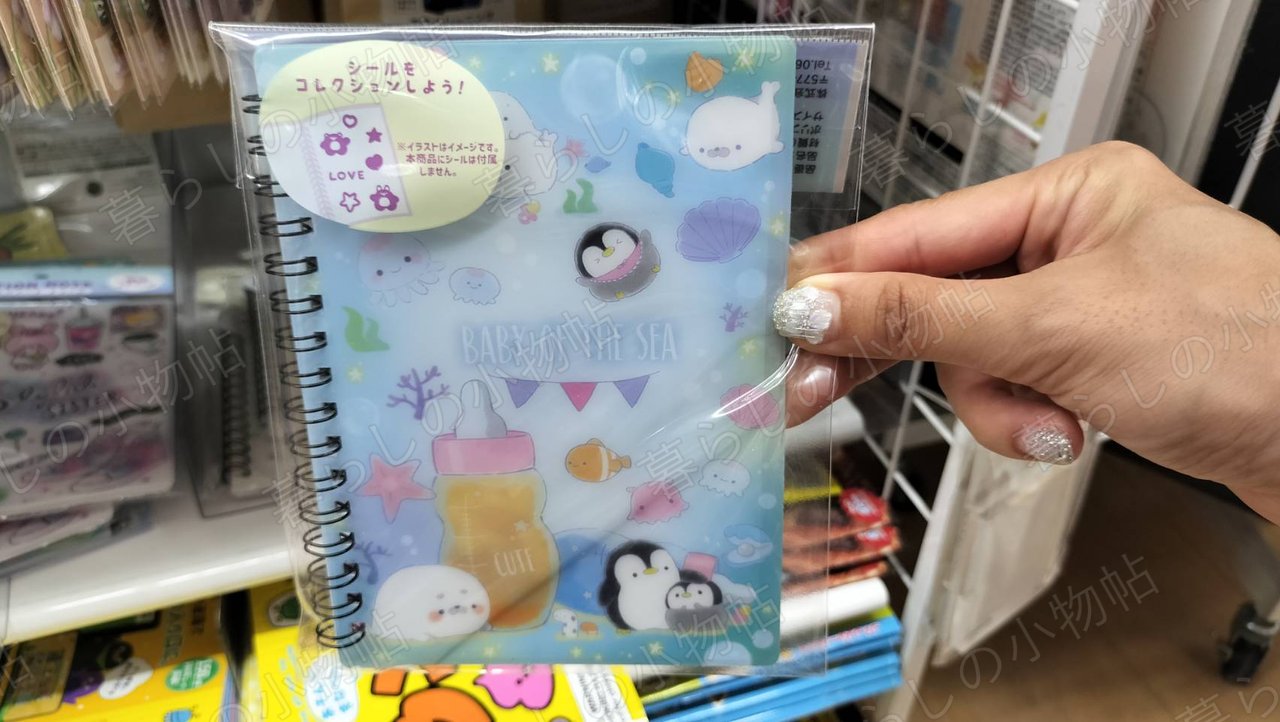 ペンギンやあざらしの赤ちゃんが描かれた水色のシール帳の表紙を手に持ったところ