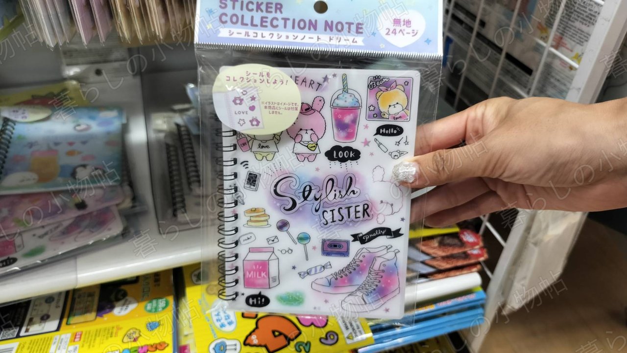 ドリーミーなイラストの「STICKER COLLECTION NOTE」表紙を手に持ったところ。無地24ページ