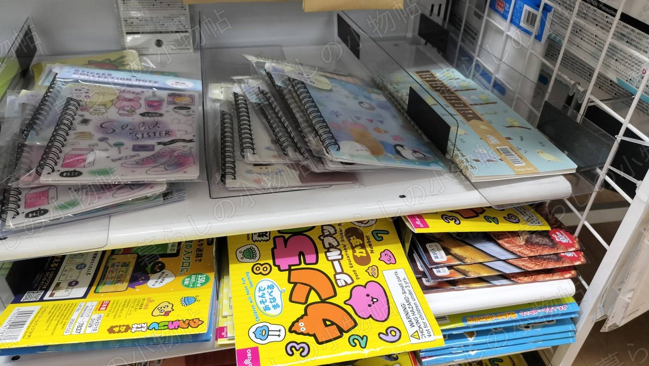 100円ショップの棚に並んだシール帳（シールコレクションブック）。表紙のデザイン違いが何種類も置かれている