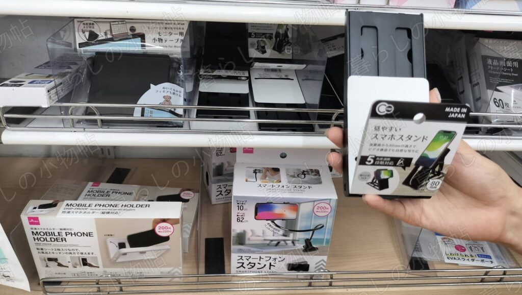 100円ショップの売り場で折りたたみ式スマホスタンドのパッケージを手に取ったところ