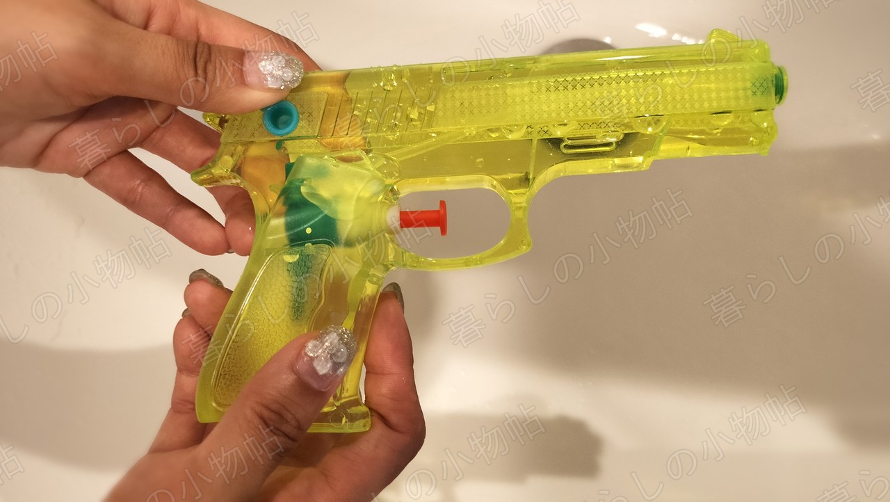 水を入れ終えて中が黄色く見える水鉄砲を両手で持ったところ