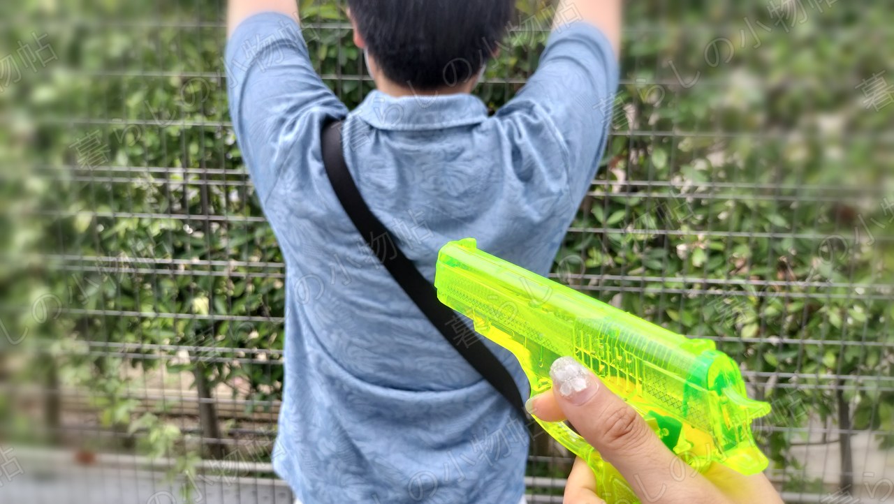 背を向けて両手を上げた家族に水鉄砲を向けたところ
